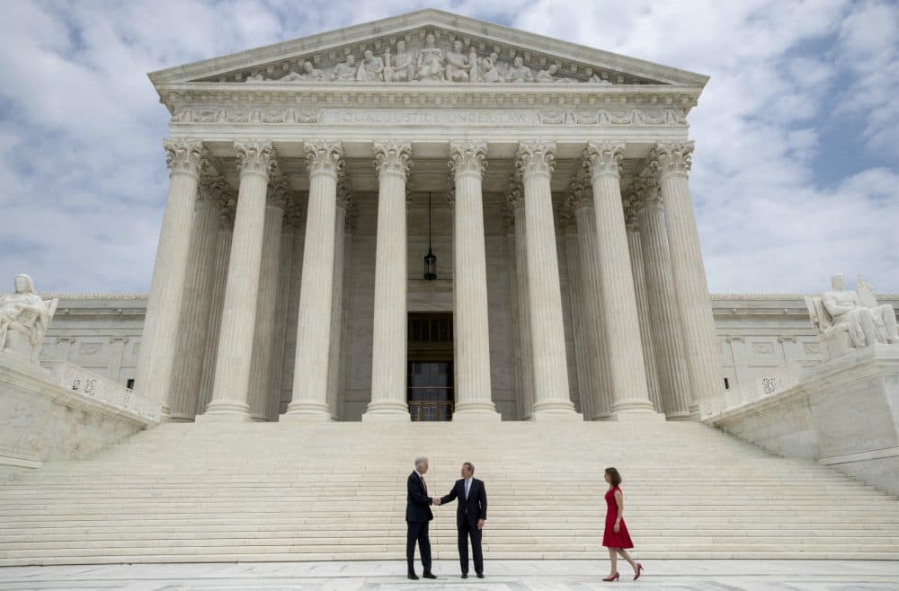 New Associate Supreme Court Justice Neil Gorsuch, left, shakes hands with Chief Justice John Roberts, as Gorsuch's wife arrives at right, at the Supreme Court, Thursday, June 15, 2017. (J. Scott Applewhite/AP)