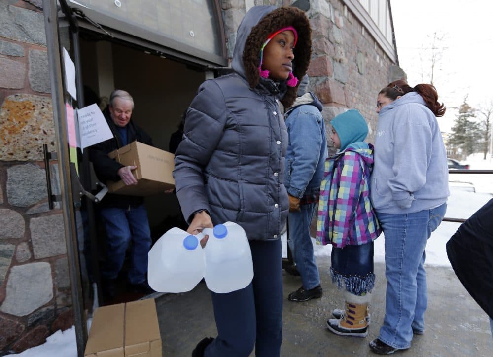 A woman carries free water being distributed in Flint, Mich, in Feb. 2015 after the city was found to be in violation of the Safe Drinking Water Act. (Paul Sancya/AP)