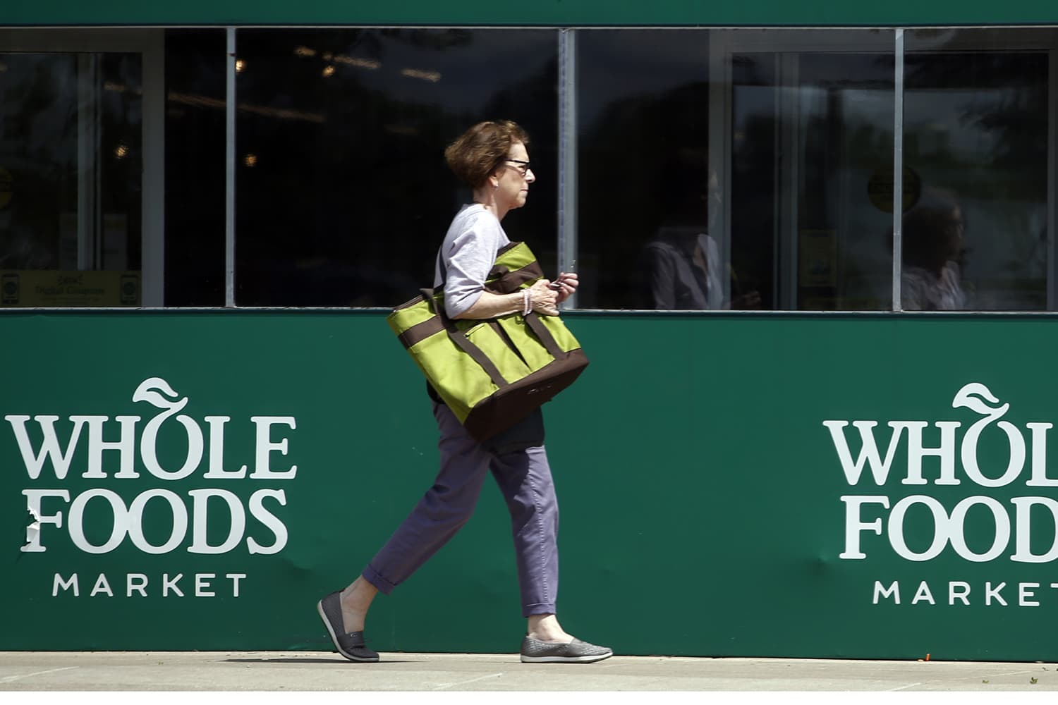 A shopper leaves a Whole Foods Market in Northbrook, Ill., Saturday, June 17, 2017. Amazon is buying Whole Foods in a deal valued at about $13.7 billion, a strong move to expand its growing reach into groceries. (Nam Y. Huh/AP)