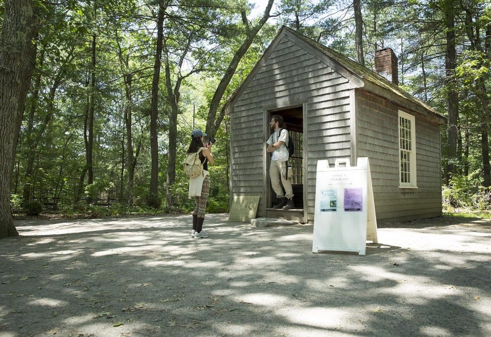 Visitors take photos of the replica of Henry David Thoreau's Walden Pond cabin. Notes Thoreau took during his time at the pond are helping scientists study climate change. (Robin Lubbock/WBUR)