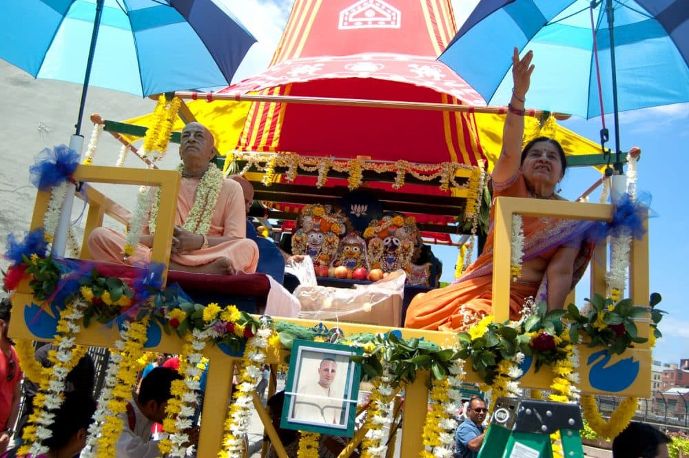 Representations of Jagannatha, “Krishna himself,&quot; and his siblings (center) sit aboard the chariot. At left is a statue of A.C. Bhaktivedanta Swami Prabhupada, the Calcutta man who brought the Hare Krishna movement to the United States. (Greg Cook/WBUR)