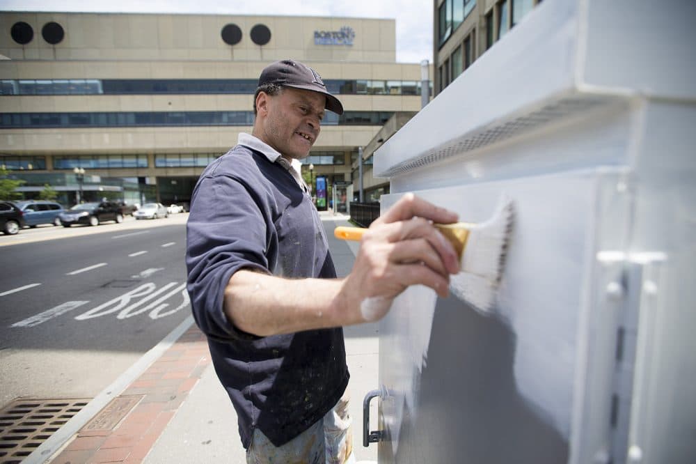 Before painting his design, artist Jeffrey Powers whitewashes an electrical box near Boston Medical Center. (Jesse Costa/WBUR)
