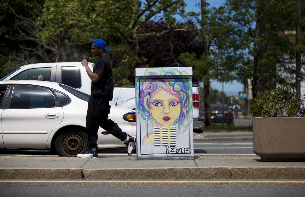 On a Mass. Ave. median, a man walks by an electrical box painted by Kitty Zen. (Jesse Costa/WBUR)