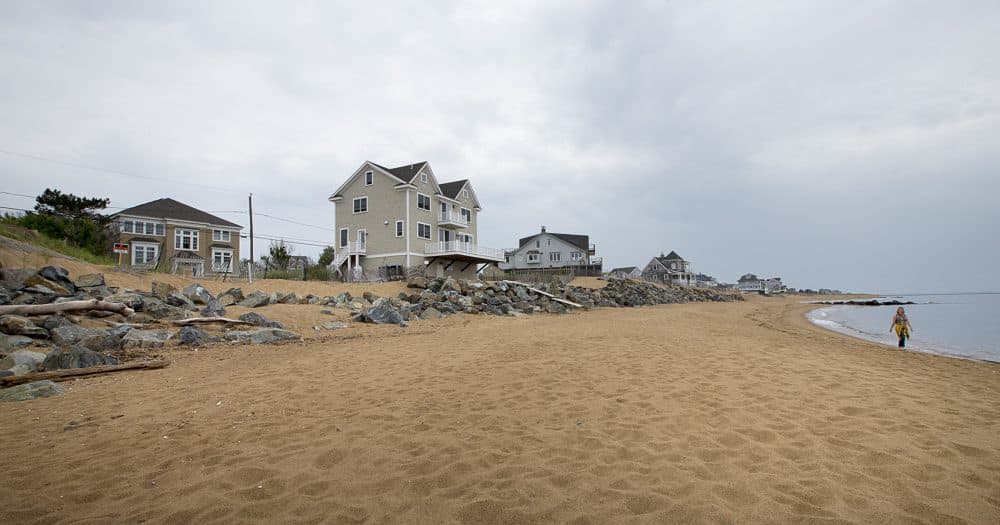 On the left is an empty lot where a beach house once stood. Successive storms during 2013 took it down. The owner has not rebuilt the house. (Jesse Costa/WBUR)