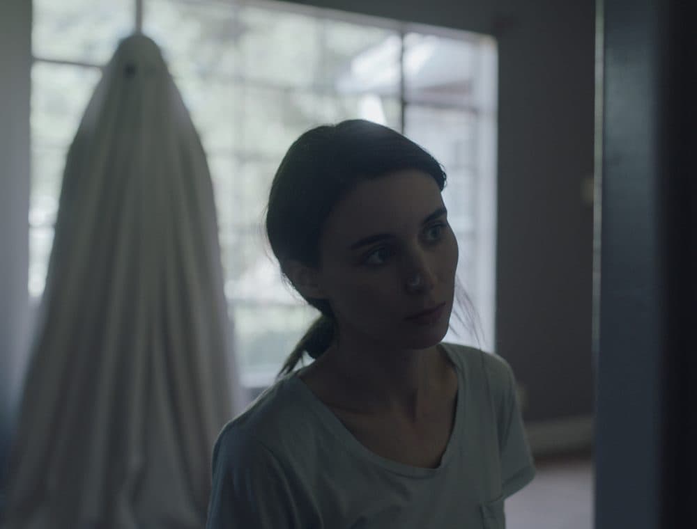 Rooney Mara with the ghost of Casey Affleck's character in the background. (Courtesy Bret Curry/A24)