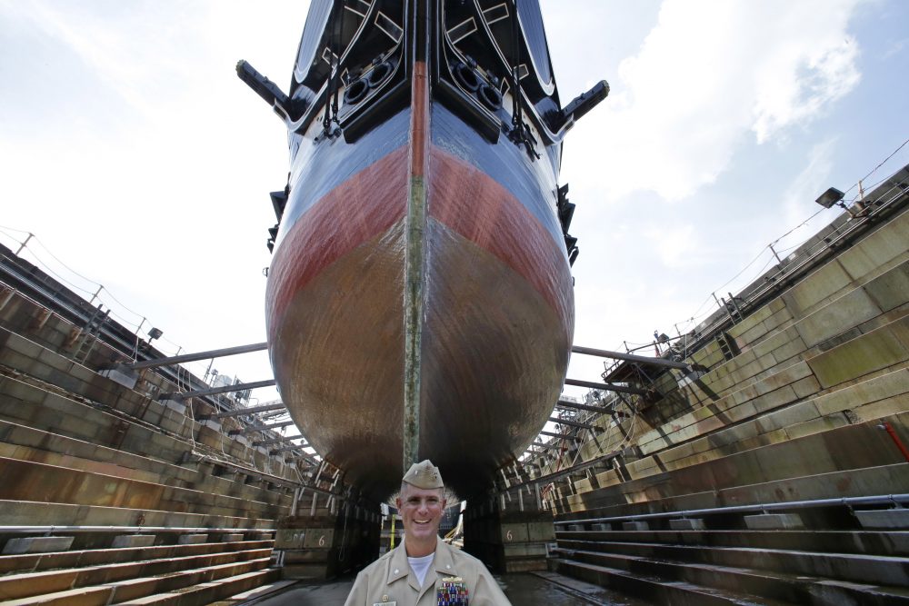 In this July 17 photo, Bob Gerosa, the 74th Commander of USS Constitution, &quot;Old Ironsides,&quot; the world's oldest commissioned warship, stands beside the vessel while it sits in dry dock after its restoration. (Stephan Savoia/AP)