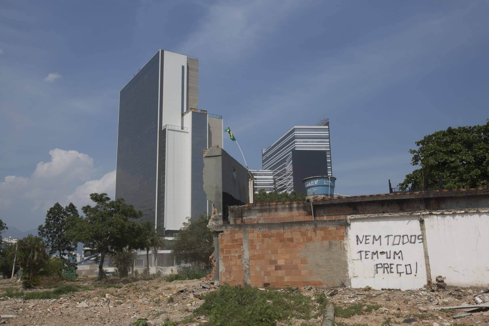 A demolished house with a sign that translates to, "Not everybody has a price" stands in front of the Olympic Media Center building. (Silvia Izquierdo/AP)