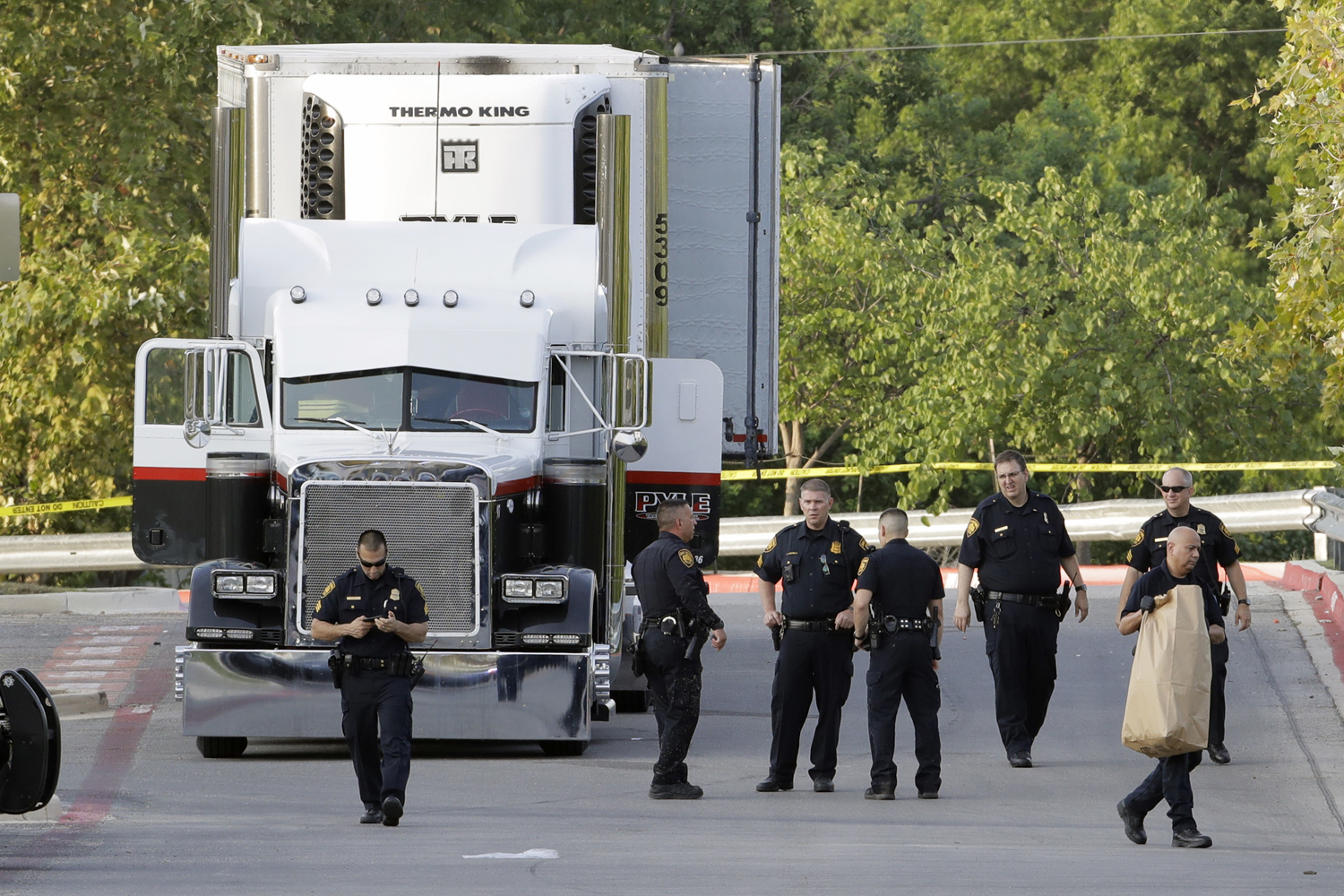 San Antonio police officers investigate the scene where eight people were found dead in a tractor-trailer loaded with at least 30 others outside a Walmart store in stifling summer heat in what police are calling a horrific human trafficking case, Sunday, July 23, 2017, in San Antonio. (Eric Gay/AP)