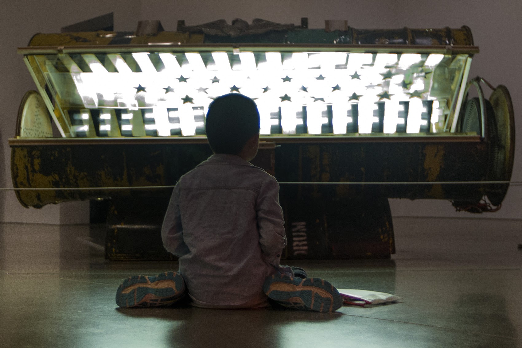 A 9-year-old boy colors on the floor in front of Nari Ward's "Tanning Bed" at the ICA. (Jesse Costa/WBUR)