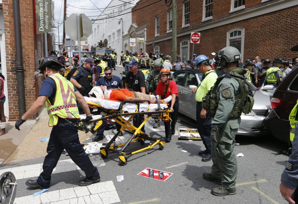 Rescue personnel help injured people after a car ran into a large group of protesters after an white nationalist rally in Charlottesville, Va., Saturday, Aug. 12, 2017. (Steve Helber/AP)