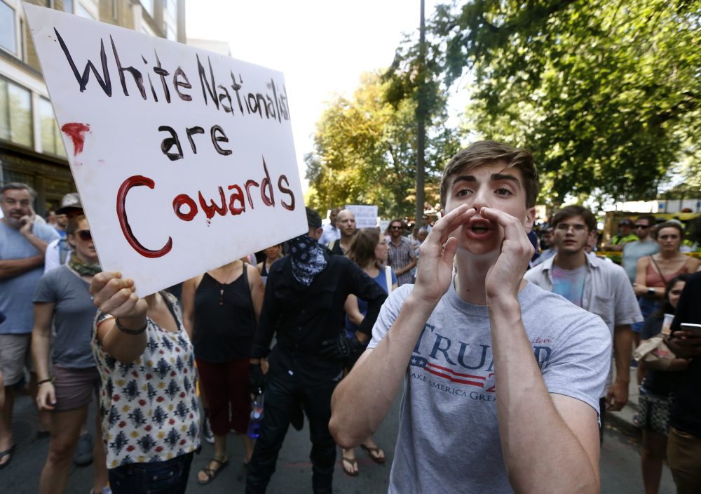 A counter-protester, left, holds a sign beside a man wearing a T-shirt bearing President Donald Trump's name. (Michael Dwyer/AP)