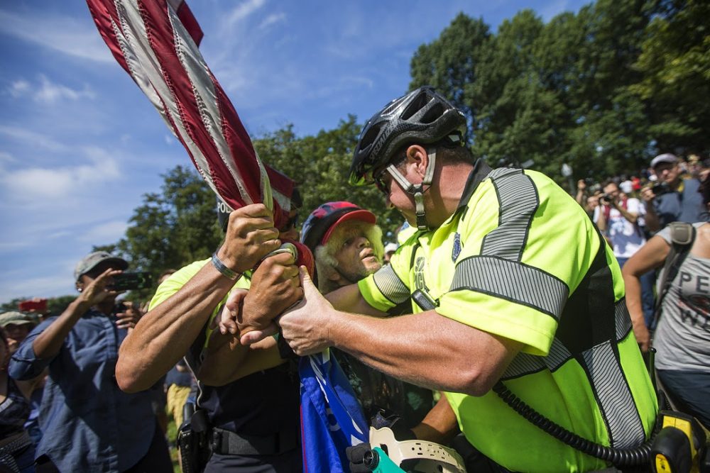Two Boston Police officers apprehend a Trump supporter involved in an altercation with several counter protesters. He was escorted out of the Boston Common for his own safety. (Jesse Costa/WBUR)