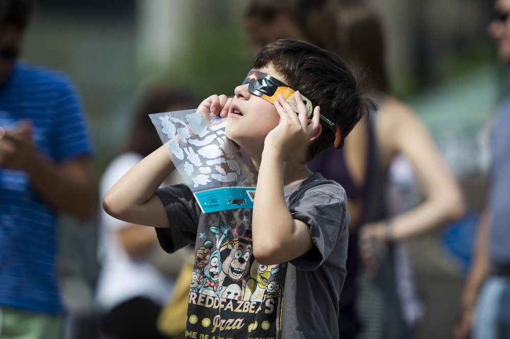 Christopher Griffith, 8, of Roslindale looks up at the solar eclipse from Copley Square. (Robin Lubbock/WBUR)