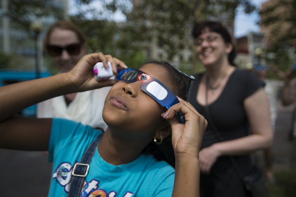 Nine-year-old Aliana Baccus takes a look at the solar eclipse in Copley Square. (Jesse Costa/WBUR)