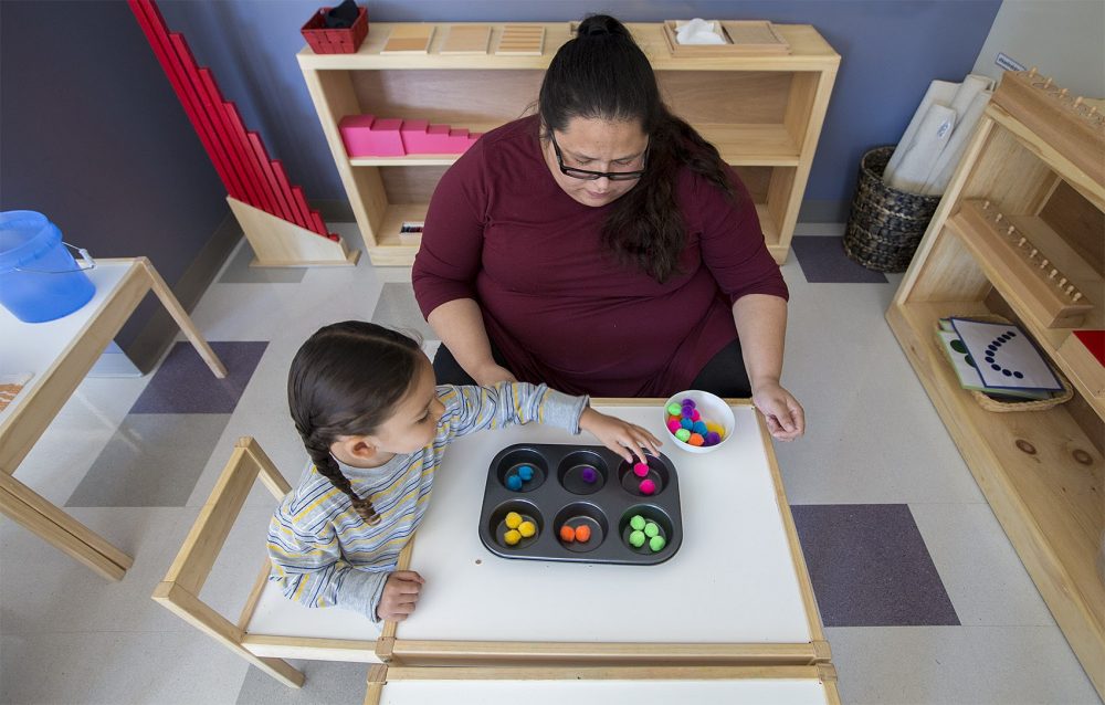 Linguist and teacher Tia Pocknett plays a color matching game with a young student. She calls out the Wampanoag names of colors as the student as she is matching the coloered balls. (Jesse Costa/WBUR)