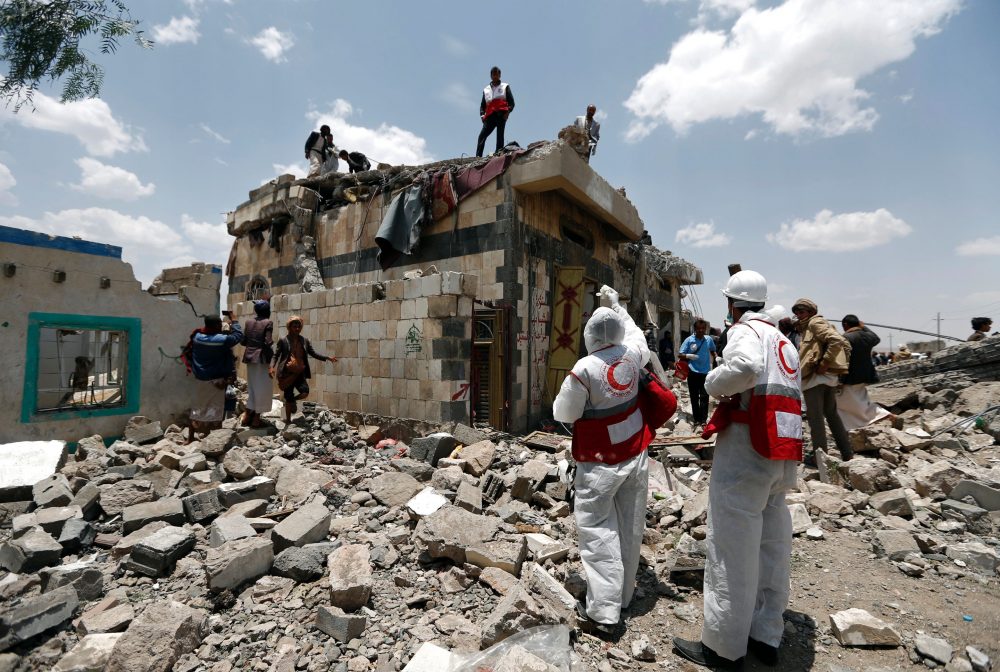 Yemeni Red Crescent workers and civilians stand at the site of an air raid in the Arhab area, around 13 miles north of Sanaa, on Aug. 23, 2017, where a Saudi-lead coalition has been bombing Iran-backed Huthi rebels. (Mohammed Huwais/AFP/Getty Images)