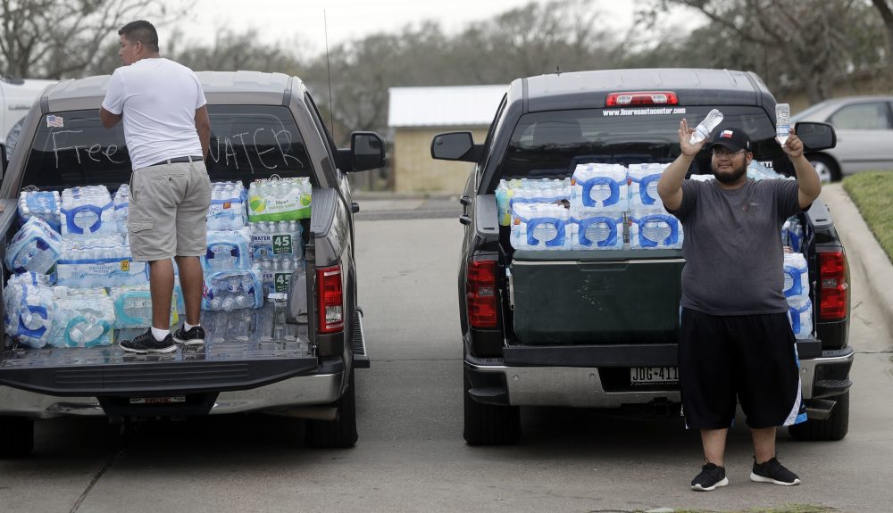 Miguel Juarez, right, offers free water to passing vehicles Sunday in Rockport, Texas. Juarez and others from the Texas Rio Grande Valley created a make-shift aid station for in need following Hurricane Harvey. (Eric Gay/AP)