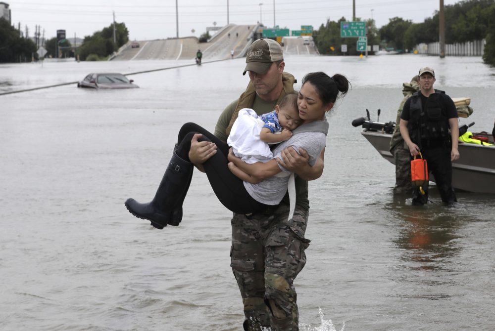 Houston Police SWAT officer Daryl Hudeck carries Catherine Pham and her 13-month-old son Aiden after rescuing them from their home surrounded by floodwaters from Tropical Storm Harvey on Sunday. (David J. Phillip/AP)