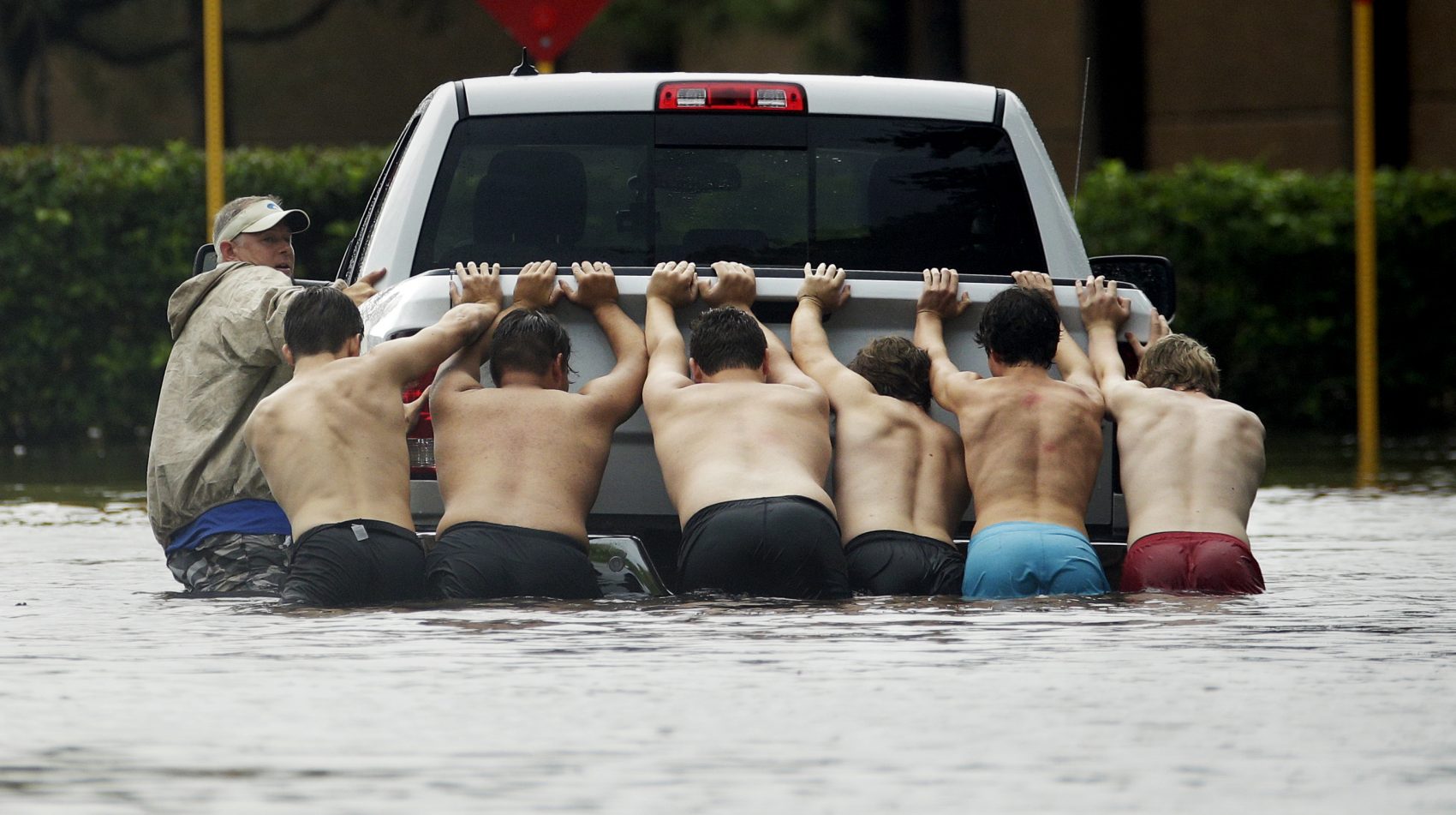 People push a stalled pickup through a flooded street in Houston, after Tropical Storm Harvey dumped heavy rains on Sunday. (Charlie Riedel/AP)