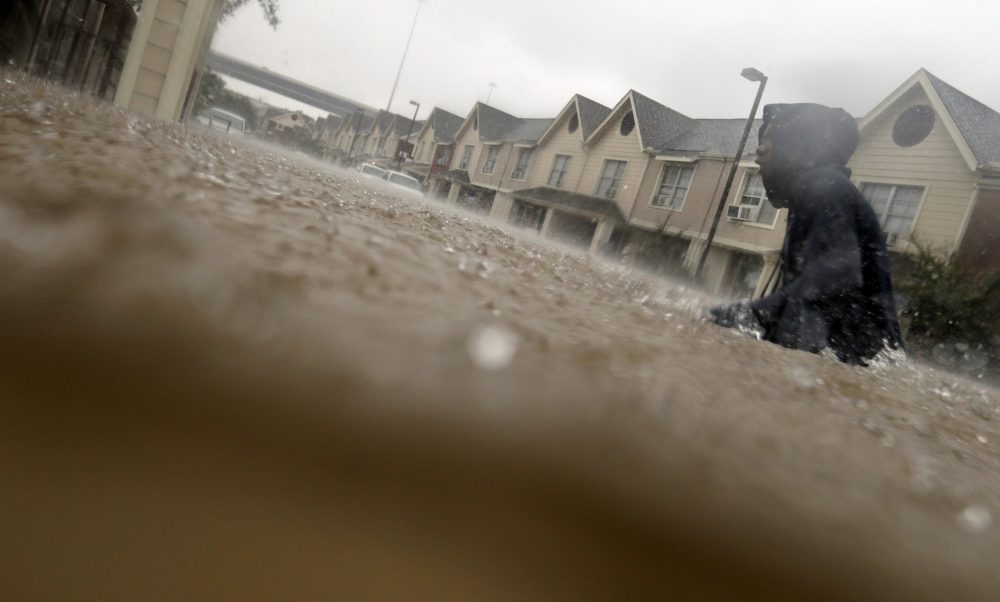 A child makes his way through floodwaters from Tropical Storm Harvey while checking on neighbors at his apartment complex in Houston on Sunday. (LM Otero/AP)