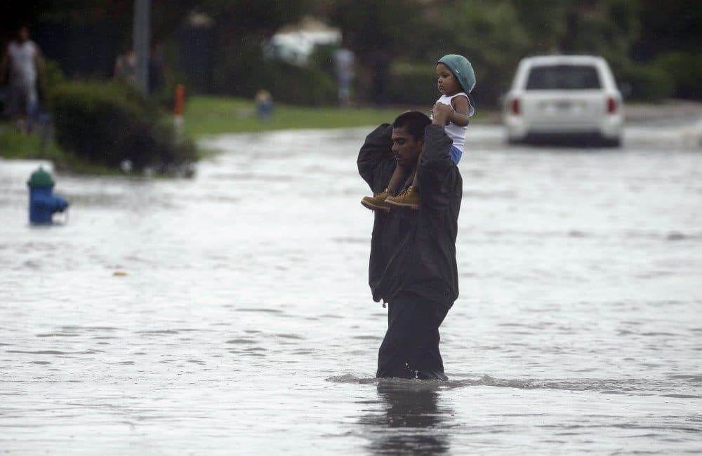 A man carries a child across a flooded street in Houston after Tropical Storm Harvey dumped heavy rains on northeast Texas on Sunday. (Charlie Riedel/AP)