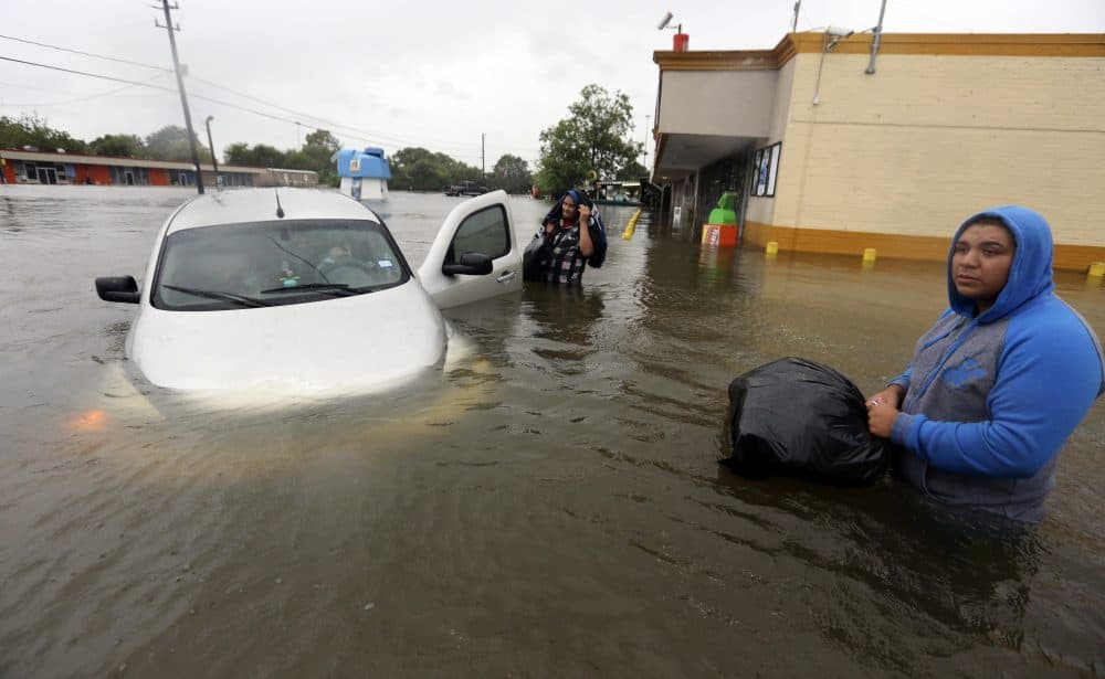 Conception Casa, center, and his friend Jose Martinez, right, check on Rhonda Worthington after her car become stuck in rising floodwaters from Harvey in Houston on Monday. The two men were evacuating their home that had become flooded when they encountered Worthington's car floating off the road. (AP Photo/LM Otero)