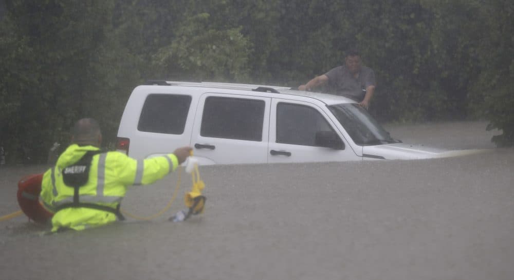 Wilford Martinez, right, waits to be rescued by Harris County Sheriff's Department Richard Wagner after his car got stuck in floodwaters in Houston. (David J. Phillip/AP)