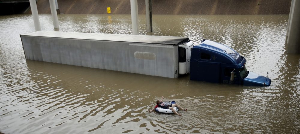 After helping the driver of the submerged truck get to safety, a man floats on the freeway flooded by Tropical Storm Harvey near downtown Houston. (Charlie Riedel/AP)