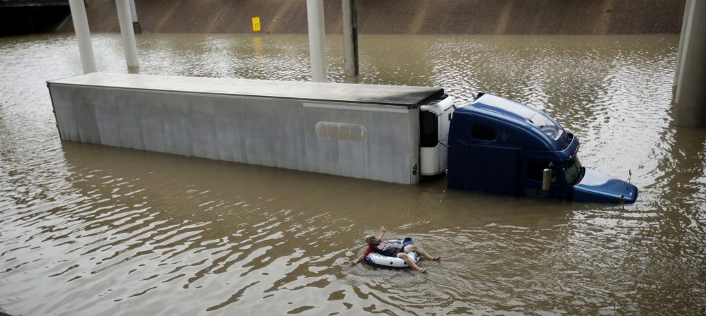 After helping the driver of the submerged truck get to safety, a man floats on the freeway flooded by Tropical Storm Harvey on Sunday, Aug. 27, 2017, near downtown Houston. (AP Photo/Charlie Riedel)