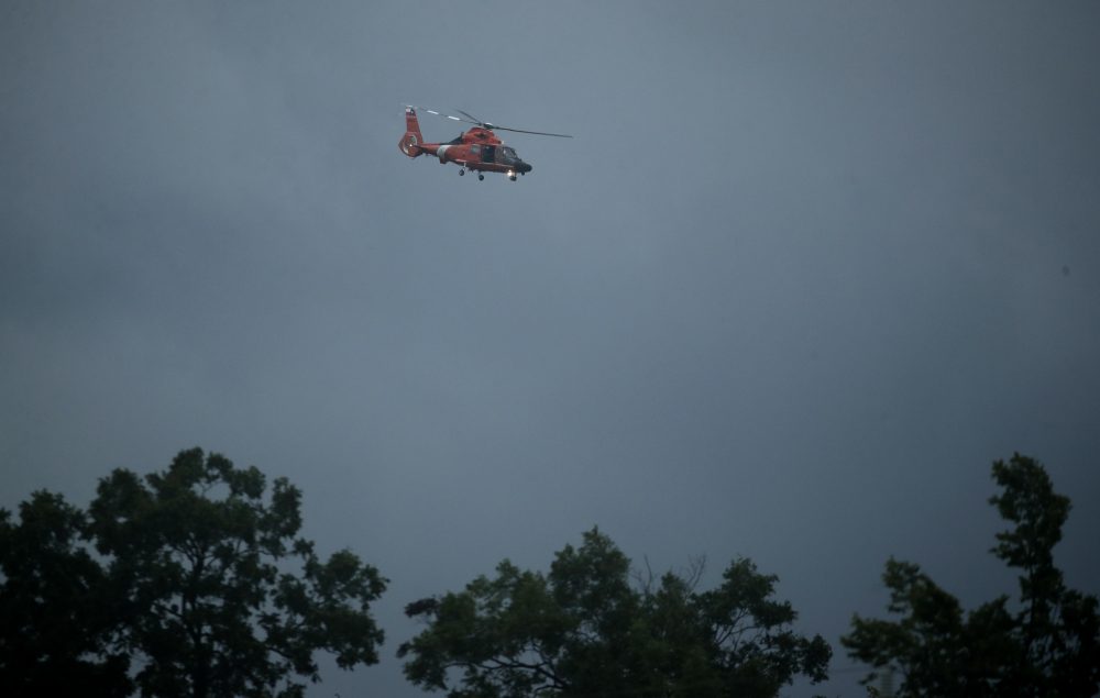 A coast guard helicopter searches a flooded neighborhood in Houston. (Charlie Riedel/AP)