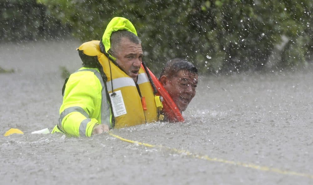 Wilford Martinez, right, is rescued from his flooded car by Harris County Sheriff&#039;s Department Richard Wagner along Interstate 610. (David J. Phillip/AP)