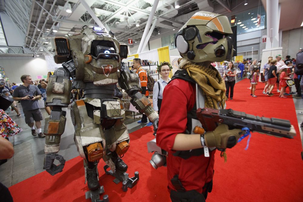 BT from Titan Fall 2, left, and its pilot walk on the display floor at Boston Comic Con, Friday, Aug. 11, 2017, in Boston. The convention is being held at the Boston Convention &amp; Exhibition Center through Sunday. (AP Photo/Michael Dwyer)