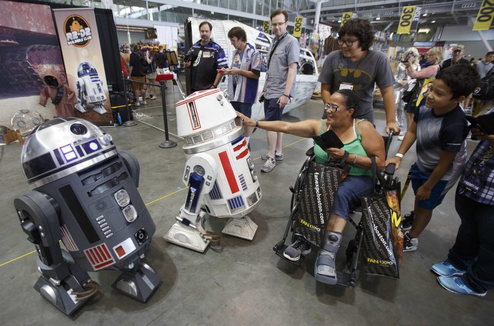 A woman interacts with remote controlled R2-D2s at Boston Comic Con, Friday, Aug. 11, 2017, in Boston. The convention is being held at the Boston Convention &amp; Exhibition Center through Sunday. (AP Photo/Michael Dwyer)