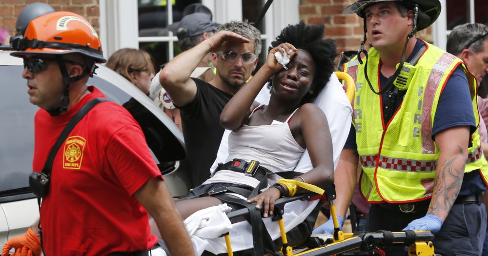 Rescue personnel help an injured woman after a car ran into a large group of protesters after an white nationalist rally in Charlottesville, Va., Saturday, Aug. 12, 2017. (Steve Helber/AP)