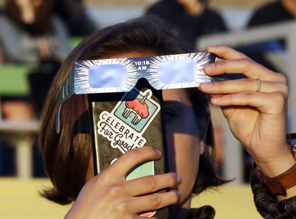 Catalina Gaitan, from Portland, Oregon, tries to shoot a photo of the rising sun through her eclipse glasses at a gathering of eclipse viewers in Salem, Oregon. (Don Ryan/AP)