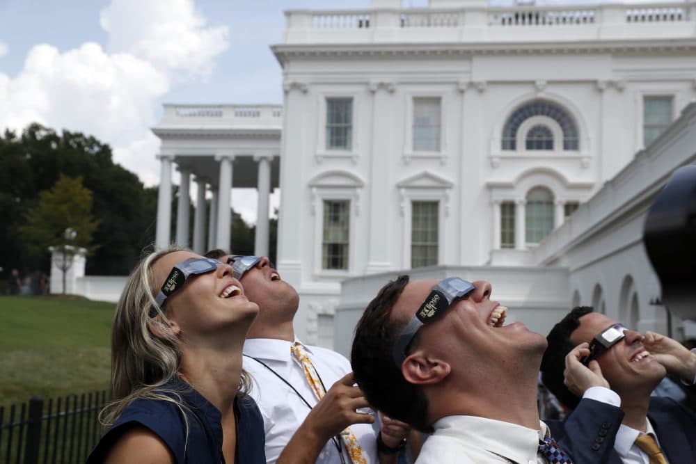 White House staff and members of the White House press corps use glasses to look at the eclipse at the White House. (Alex Brandon/AP)