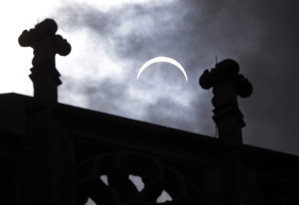 The moon is seen passing in front of the sun during a solar eclipse over the roof of the Scottish Rite Cathedral in Indianapolis. (Michael Conroy/AP)