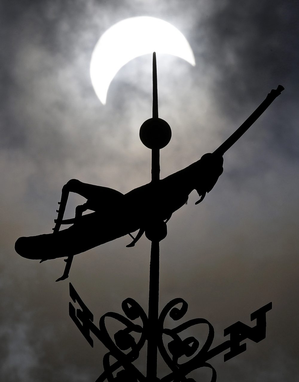 The partial solar eclipse passes over the golden grasshopper weathervane atop Faneuil Hall. (Charles Krupa/AP)