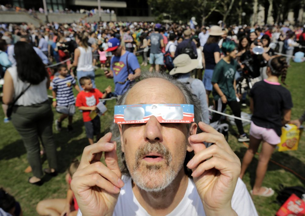 Robert Arthur, of Watertown, uses protective eclipse glasses to view the partial solar eclipse from the MIT campus. (Steven Senne/AP)