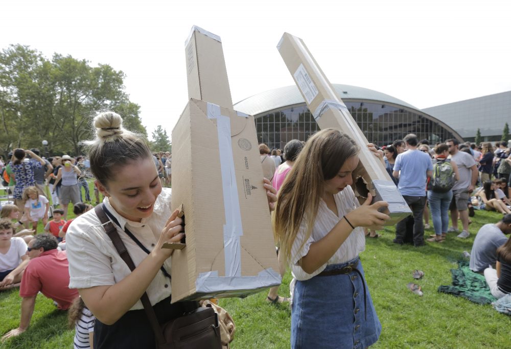Reveka Pasternak, of Boston, left, and her sister Tristen, of Philadelphia, use pinhole projectors to view the eclipse from MIT. (Steven Senne/AP)