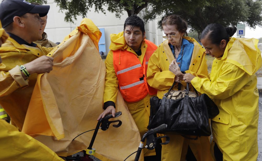 Martha Wilson, second from right, is helped by city officials as she is evacuated with others as the outer bands of Hurricane Harvey begin to make landfall, Friday, Aug. 25, 2017, in Corpus Christi, Texas. Harvey intensified into a hurricane Thursday and steered for the Texas coast with the potential for up to 3 feet of rain, 125 mph winds and 12-foot storm surges in what could be the fiercest hurricane to hit the United States in almost a dozen years. (AP Photo/Eric Gay)