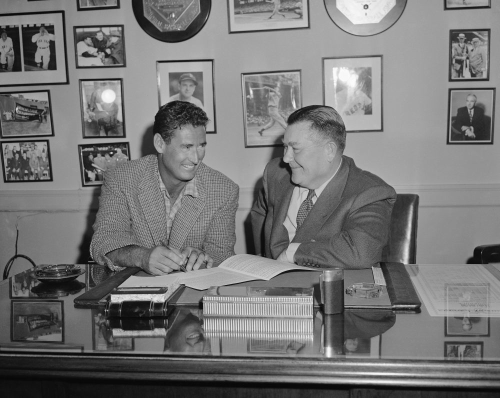 Ted Williams, left, smiles happily after he signed his contract to play another year for the Boston Red Sox as owner Tom Yawkey beams happily back in an office at Fenway Park, Feb. 4, 1956. (Peter J. Carroll/AP)
