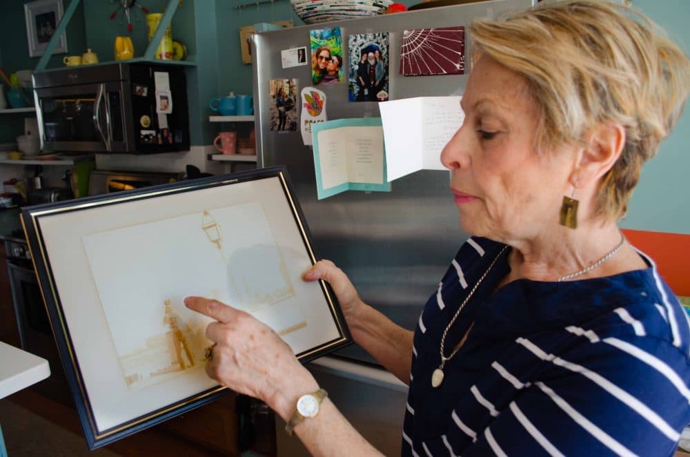 East Boston resident Michele Modica shows a framed picture of her family standing on the shore behind her house when you can clearly see an undeveloped Boston skyline. (Elizabeth Gillis/WBUR)