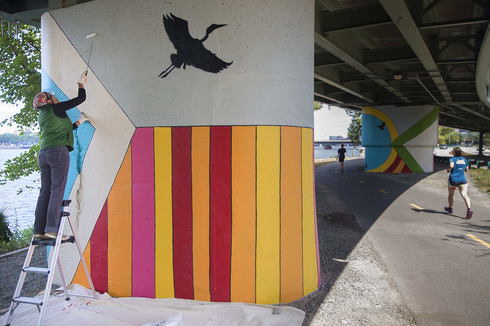 Artist Silvia López Chavez applies an anti-graffiti solution to her mural on the Esplanade's Dr. Paul Dudley White Bike Path. (Jesse Costa/WBUR)