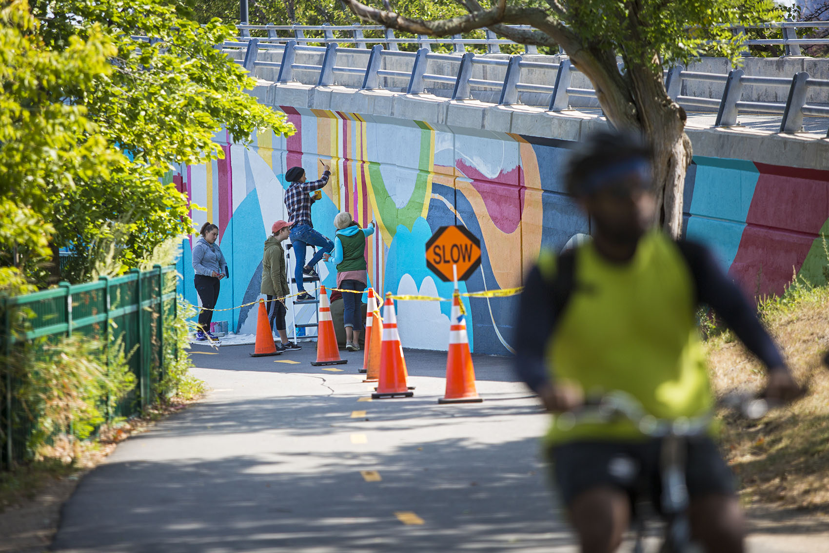 Artist Silvia López Sanchez and her crew of artist volunteers work on the main section of the mural on the Bowker Overpass above the bike path. (Jesse Costa/WBUR)