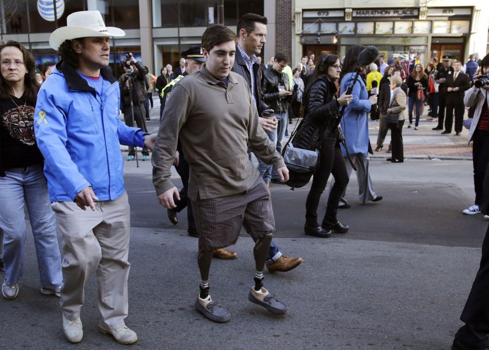 Boston Marathon survivor Jeff Bauman, right, walks past one of two blast sites with Carlos Arredondo, who helped save his life, near the finish line of the Boston Mararthon in Boston, Wednesday, April 15, 2015. (Charles Krupa/AP)