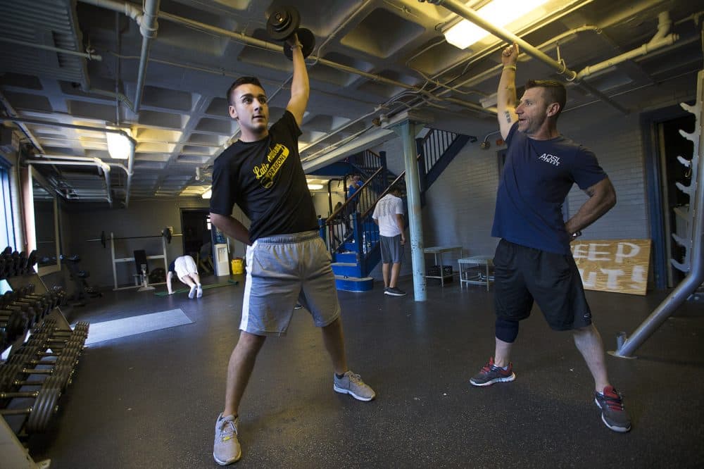 Jeff Buckley demonstrates to Joe Doyle how to lift weights properly. (Jesse Costa/WBUR)