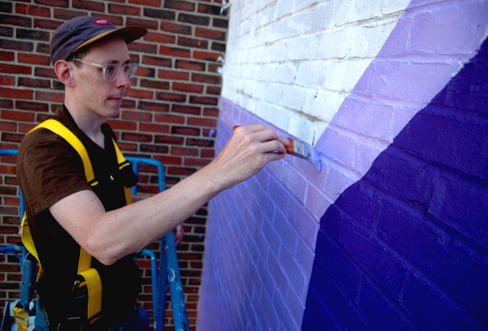 High up on a lift, Tim McCool works on his sunrise mural at 774 Albany St., Boston, on Sept. 24, 2017. (Greg Cook)