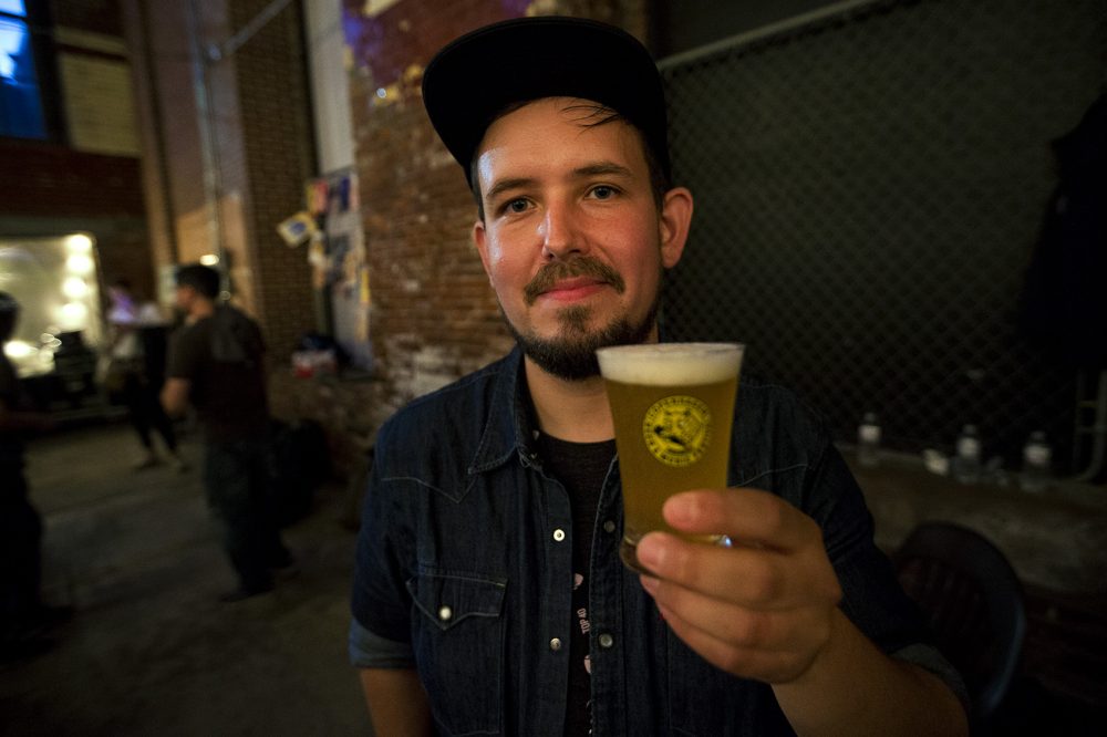Andreas Skytt Larsen, of Alefarm Brewing, holds a glass of his Mimesis Saison. (Jesse Costa/WBUR)