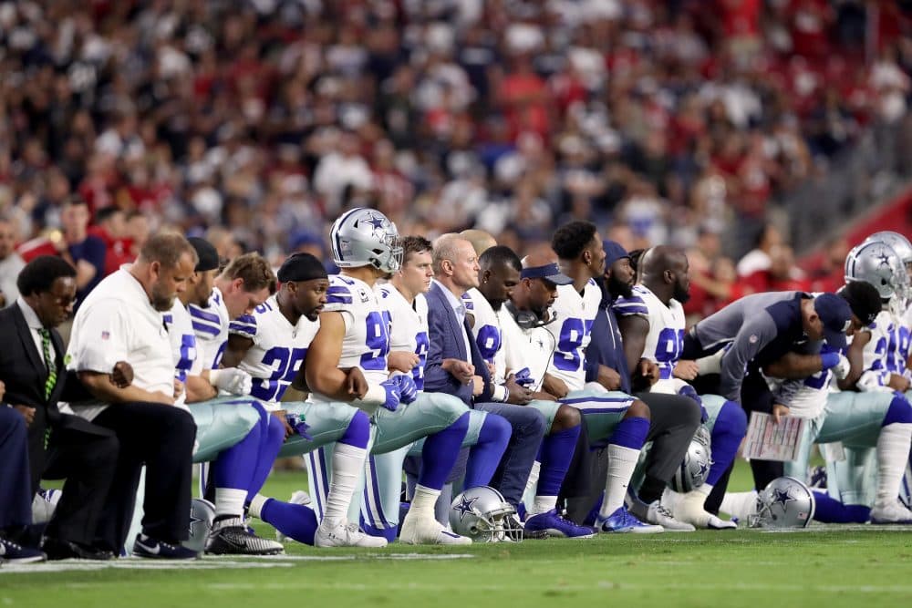 Members of the Dallas Cowboys link arms and kneel during the National Anthem before the start of their game against the Arizona Cardinals (Christian Petersen/Getty Images)